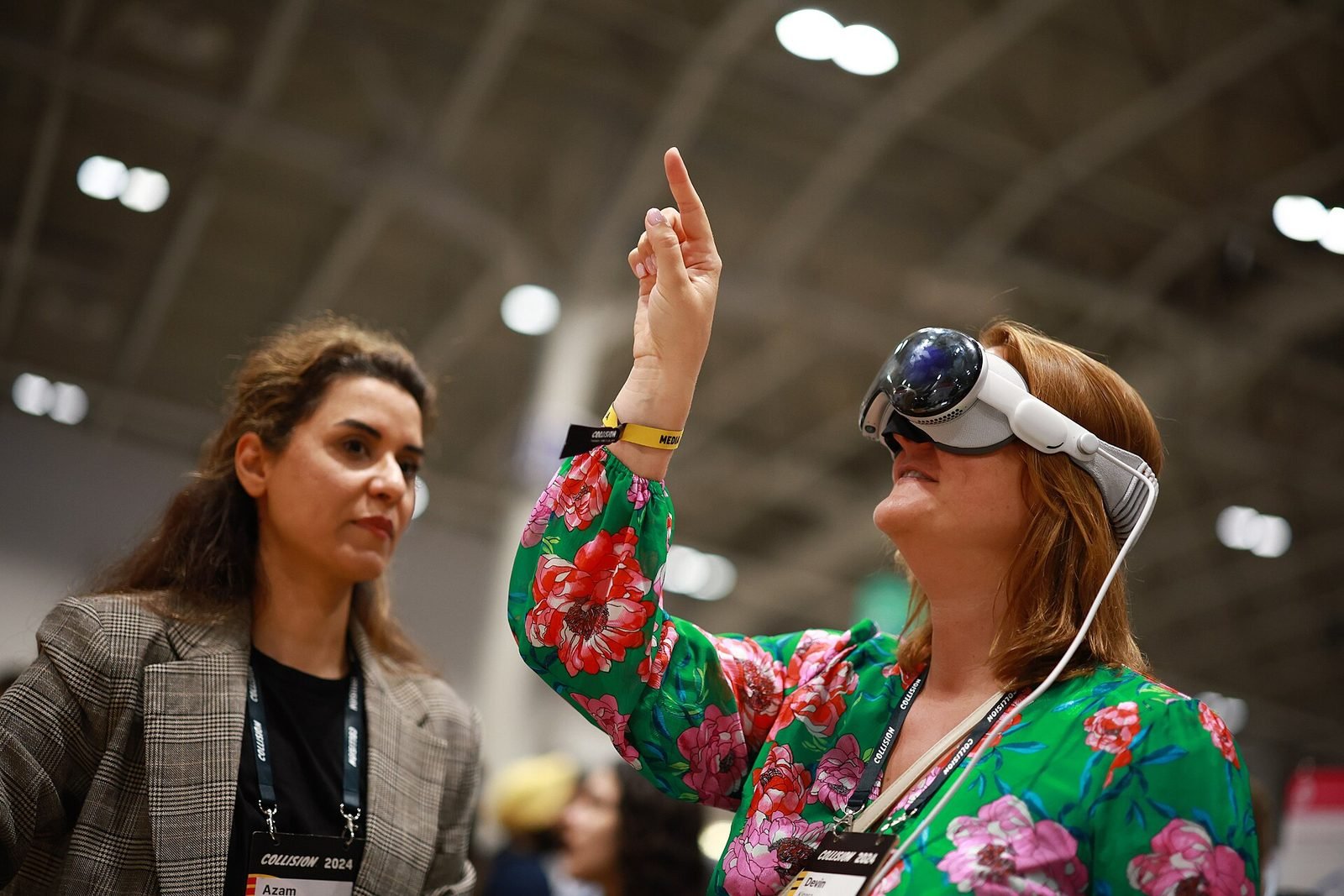 Two people at an event, one wearing a spatial headset, talking while gesturing
