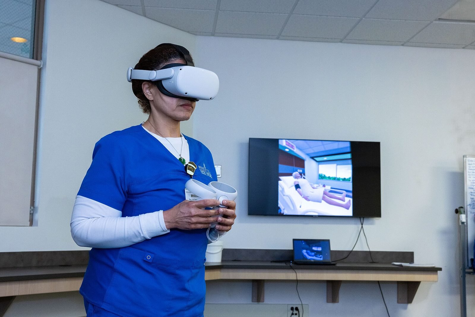 A nurse wearing a VR headset next to a screen mirroring the virtual scene