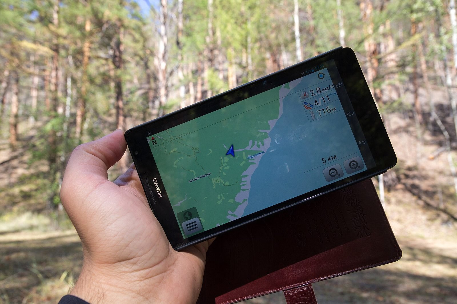 A hand holding a tablet with a GPS map while walking outdoors