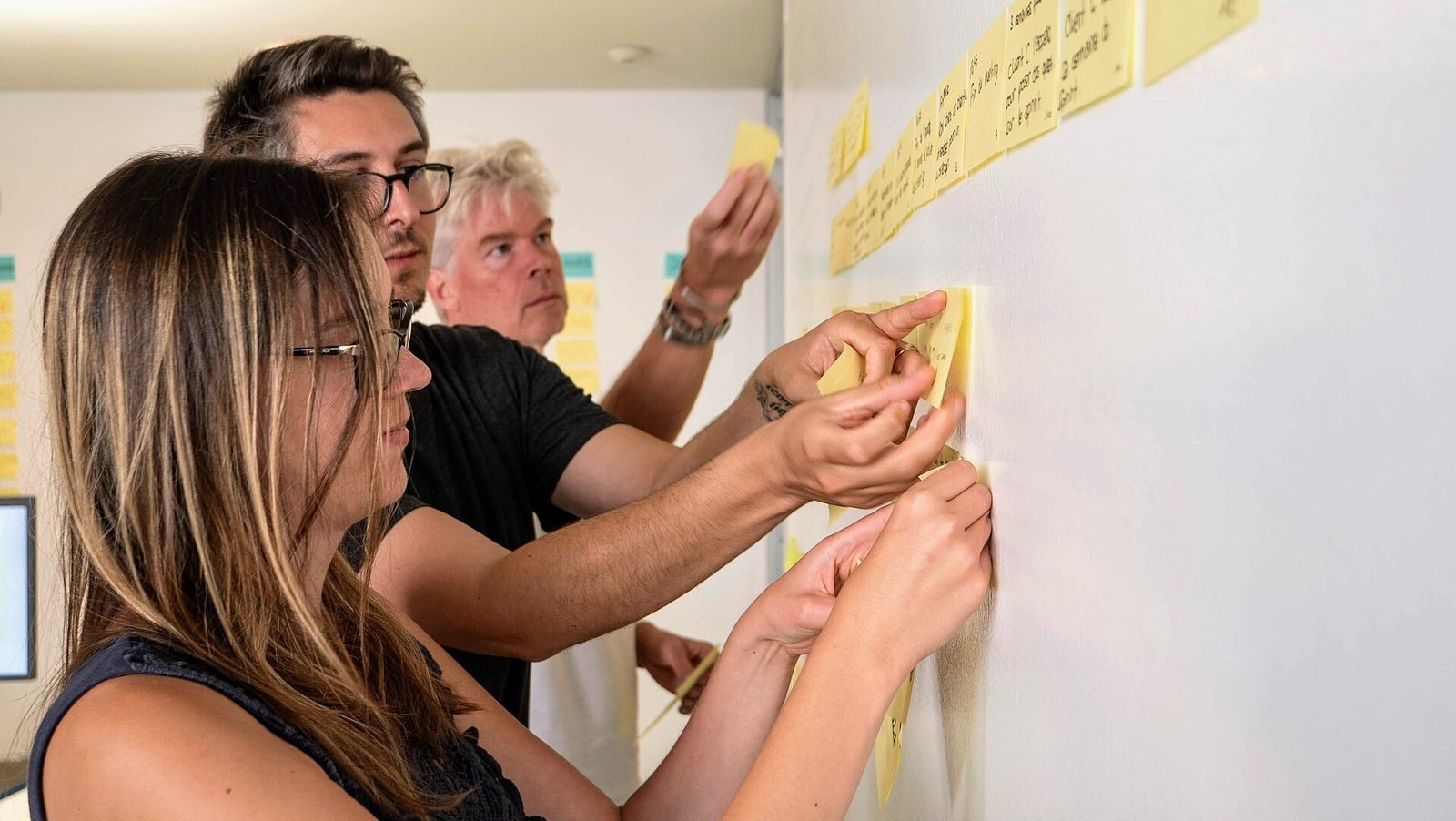 A team placing sticky notes on a wall during a research workshop